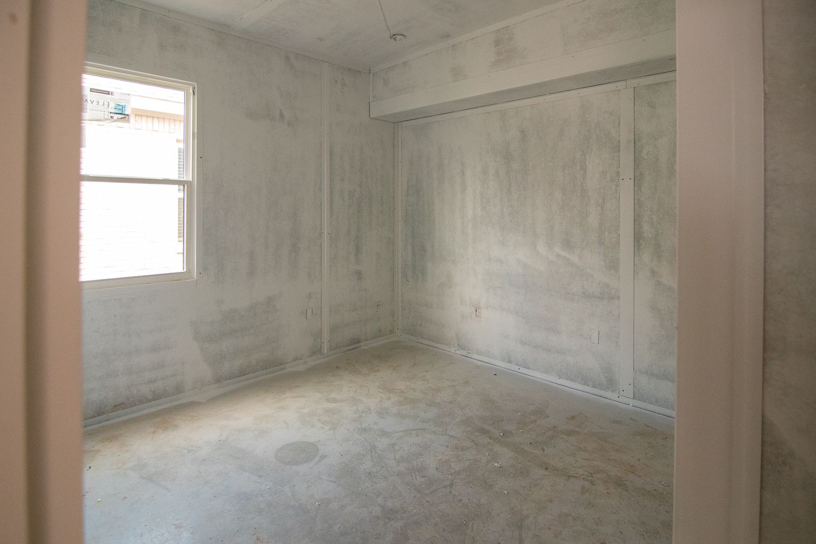Interior room framed by bare composite panels with a window opening