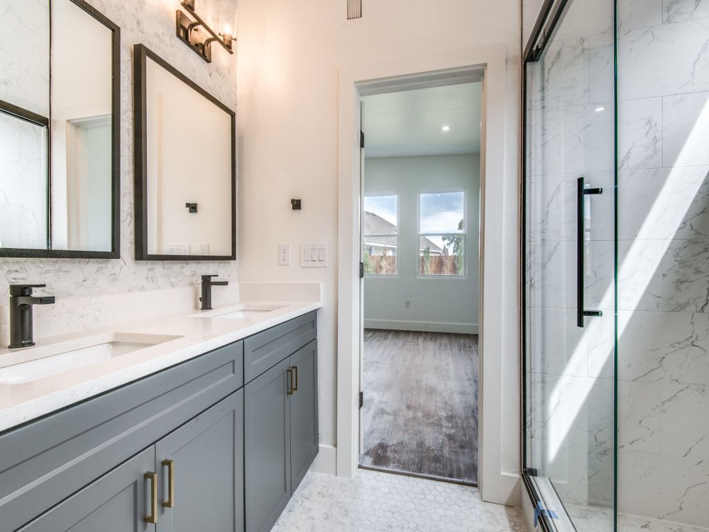 Bathroom with double vanity, black fixtures, and glass shower