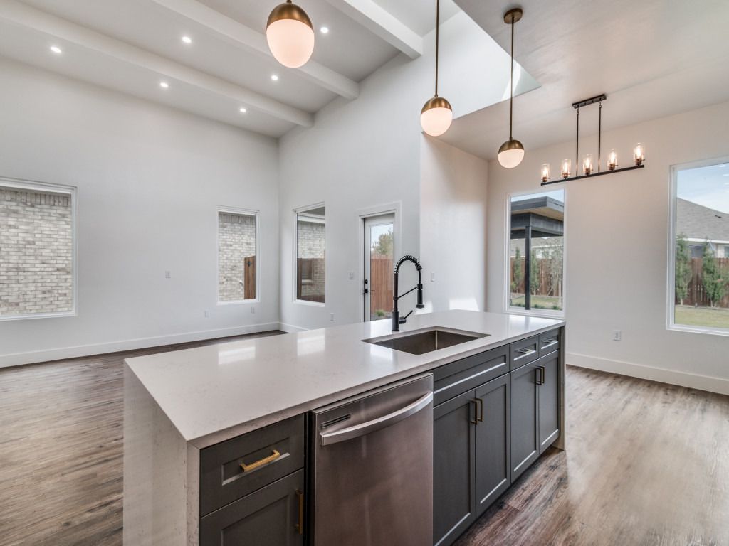 Open kitchen with a large island, pendant lights, and wood-look floors