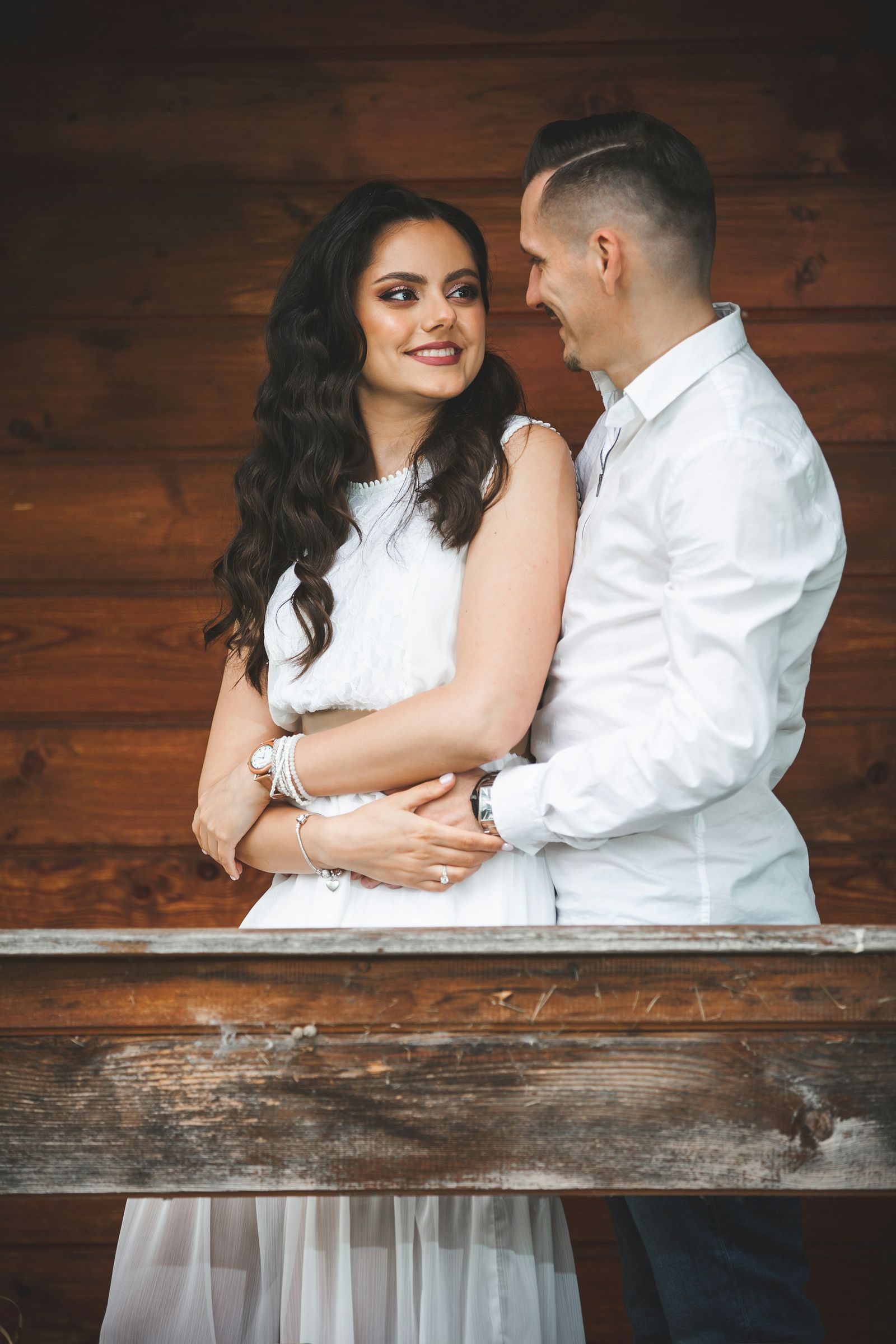 Smiling couple embracing on a wooden porch at sunset