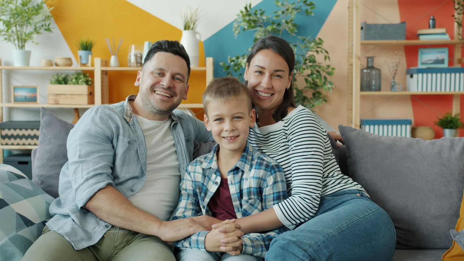 Smiling family of three relaxing together on a living room sofa