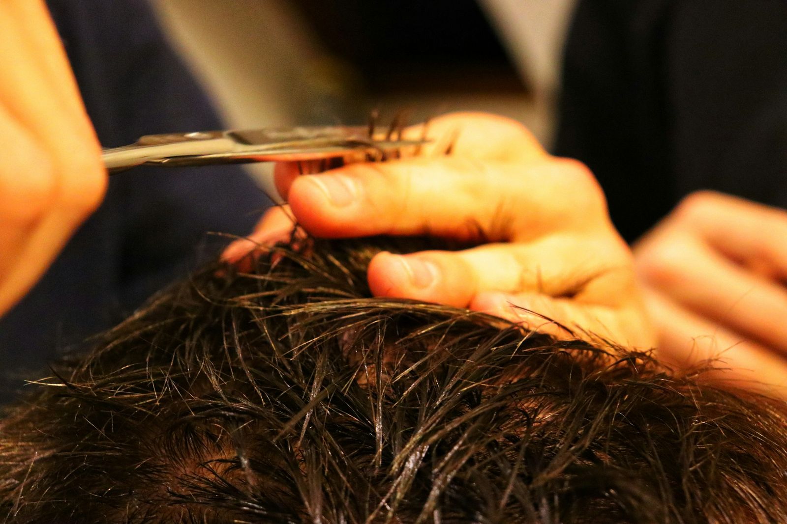 Stylist trimming a client’s hair with scissors in a small studio